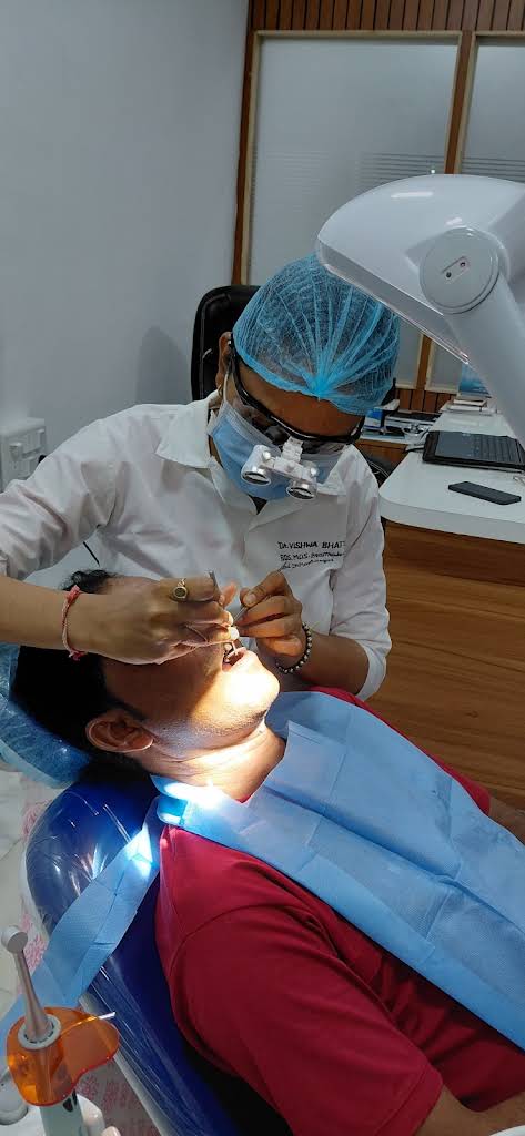 Dr. Vishwa Bhatt examining a patient with dental loupes at Pragati